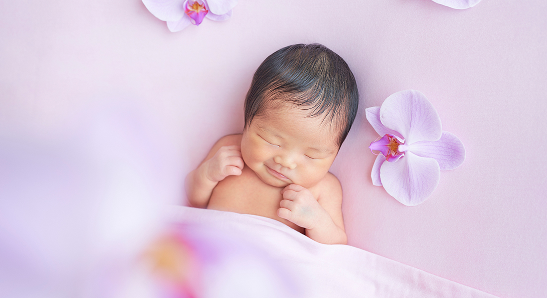 糸島写真館のシンプルニューボーンフォトでコチョウランと一緒に写る赤ちゃん