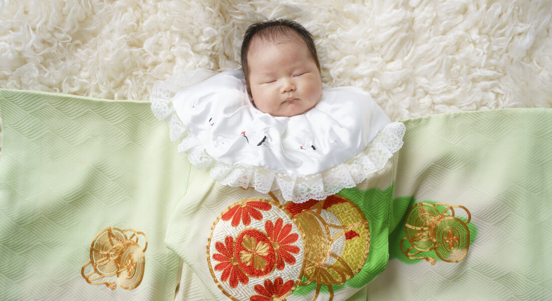 糸島写真館のお宮参りフォトで緑の着物と写る女の赤ちゃん。